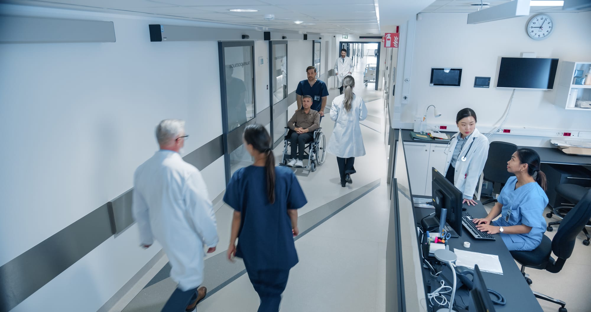 Klinikflur mit Pflegepersonal, Ärzten und Patiententransport am Stationsstützpunkt